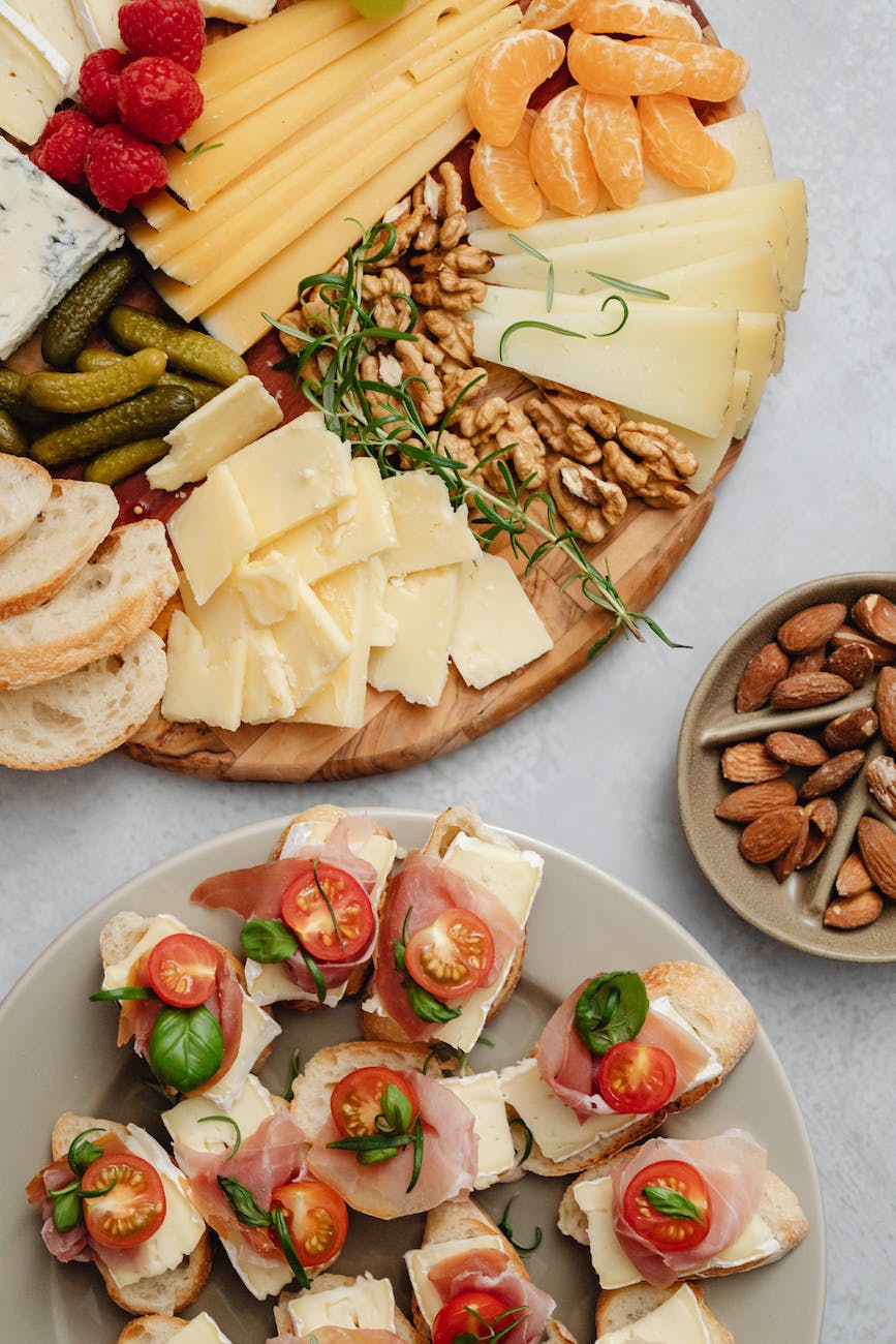 an assorted food on a charcuterie board and ceramic plate